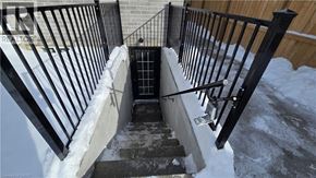 London apartment for rent - A staircase with a black railing and steps leading down to a door.