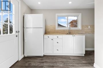 Thorold (Thorold Downtown) duplex for rent - A kitchen with white appliances and cabinets is shown.