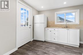 Thorold (Thorold Downtown) duplex for rent - A kitchen with a white fridge and cabinets.