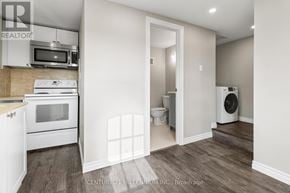Thorold (Thorold Downtown) duplex for rent - A kitchen with a microwave, oven, and a washing machine.