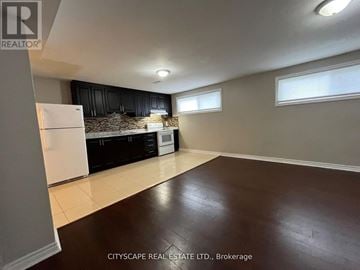 Brampton (Northwood Park) apartment for rent - A kitchen with black cabinets and a white fridge is shown.