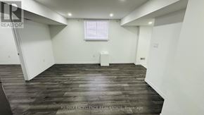 Kitchener apartment for rent - A spacious room with wooden flooring and white walls.