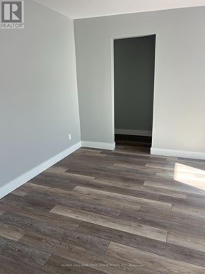 Oshawa (Lakeview) multi-family for rent - A room with a wooden floor and a door on the right side.