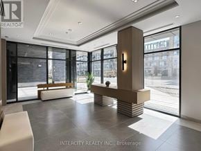 Toronto (Bathurst Manor) condo for rent - A living room with a large grey sofa, a round coffee table, and a large plant in the center.