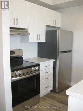 Niagara Falls (Morrison) townhouse for rent - A kitchen with a stove top oven, refrigerator, and cabinets.
