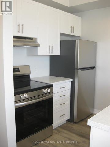 Niagara Falls (Morrison) townhouse for rent - A kitchen with a stove top oven, refrigerator, and cabinets.