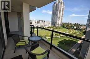 Burnaby apartment for rent - A balcony with a table and chairs overlooks a green field and buildings.