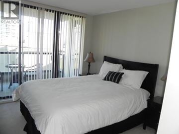 Burnaby apartment for rent - A bedroom with a large bed and a balcony with a glass railing.