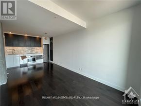 Ottawa condo for rent - A spacious room with a kitchen area in the background.