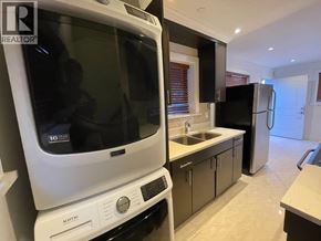 Vancouver apartment for rent - A white Maytag dishwasher is in a kitchen with black appliances.