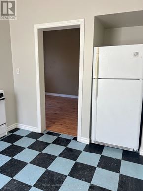 Oshawa (Lakeview) multi-family for rent - A black and white checkered floor in a room with a white fridge and a doorway.