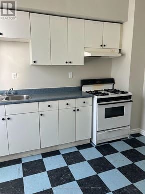 Oshawa (Lakeview) multi-family for rent - A kitchen with white cabinets and a black and white checkered floor.