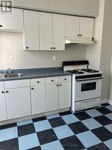 Oshawa (Lakeview) multi-family for rent - A kitchen with white cabinets and a black and white checkered floor.