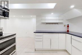 Ajax (Central West) apartment for rent - A kitchen with white cabinets and a black countertop.