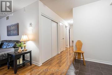 Barrie (Sunnidale) condo for rent - A living room with a black couch and a wooden chair.