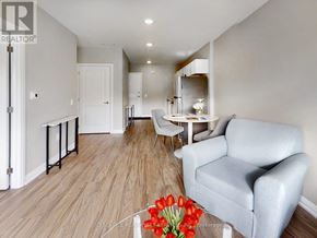 Kawartha Lakes (Lindsay) multi-family for rent - A living room with a grey couch, a white table, and a vase of red tulips.
