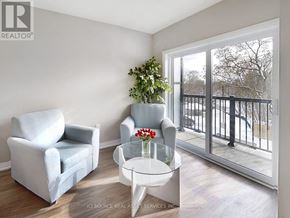 Kawartha Lakes (Lindsay) multi-family for rent - A living room with a grey couch, a white chair, and a glass table with a vase of flowers on it.