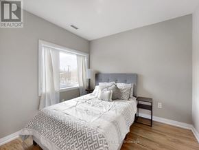 Kawartha Lakes (Lindsay) multi-family for rent - A bedroom with a large bed and a window with white curtains.