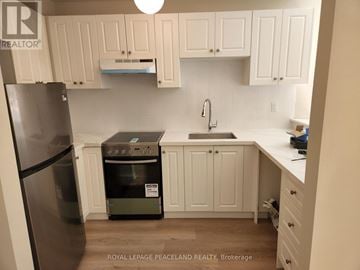 Toronto (University) multi-family for rent - A kitchen with white cabinets and a black fridge.