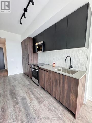 Toronto (Centennial Scarborough) condo for rent - A modern kitchen with dark wood cabinets and a stainless steel sink.