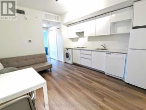 Waterloo condo for rent - A modern kitchen with white appliances and a wooden floor.