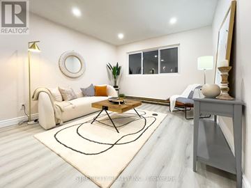 London East (East M) multi-family for rent - A living room with a white couch, a coffee table, and a rug with a black design on it.
