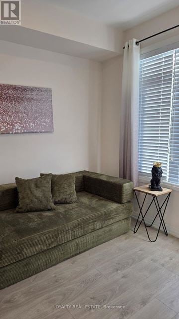 Clarington (Bowmanville) townhouse for rent - A living room with a green couch and a small table with a vase on it.