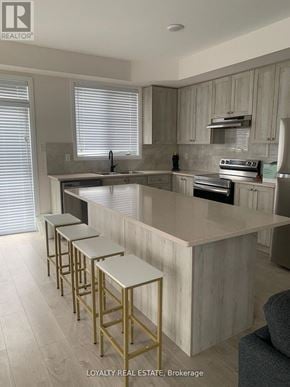 Clarington (Bowmanville) townhouse for rent - A kitchen with a white countertop and gold bar stools.