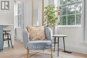 Port Hope apartment for rent - A living room with a grey armchair, a small table, and a potted plant.