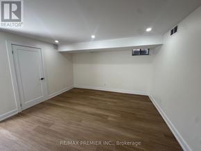 New Tecumseth (Tottenham) apartment for rent - A room with wooden flooring and white walls, with a door on the left and a small window on the right.