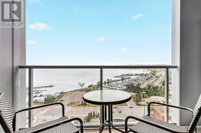 Barrie (City Centre) condo for rent - A balcony with a table and chairs overlooking a parking lot and a body of water.