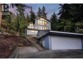Lions Bay apartment for rent - A house with a garage is surrounded by trees.