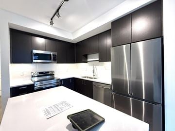 Surrey apartment for rent - A modern kitchen with a white counter top and stainless steel appliances.