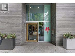 Vancouver apartment for rent - The entrance to a building with a glass door and a red flower decoration on the wall.