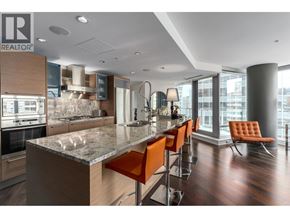 Vancouver apartment for rent - A modern kitchen with a marble countertop and orange bar stools.