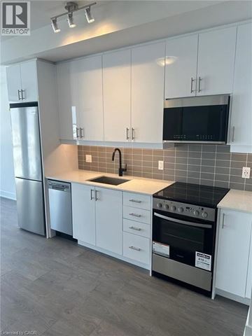 Oakville condo for rent - A kitchen with white cabinets and a black countertop.