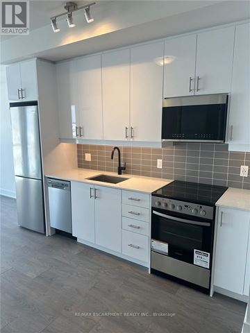 Oakville (Wm Westmount) condo for rent - A kitchen with white cabinets and a black countertop.