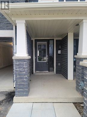 Brantford townhouse for rent - A house entrance with a dark blue door and a stone pillar.
