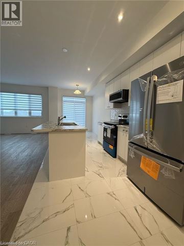 Welland townhouse for rent - A modern kitchen with a marble floor and a refrigerator with a paper taped to it.