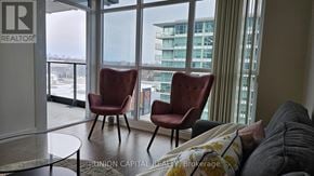 Toronto (Bayview Village) condo for rent - Two red chairs are placed in front of a window with a view of a building.