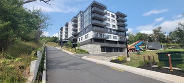 Halifax apartment for rent - A modern apartment building is situated on a tree-lined street.