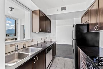 Vancouver apartment for rent - A kitchen with a black refrigerator and stove top oven.