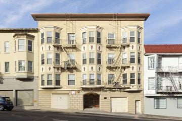 San Francisco apartment for rent - A tan building with a red roof is to the right of a tan building with a blue sky in the background.