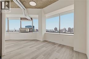 Kitchener condo for rent - A spacious room with a view of the cityscape through large windows.