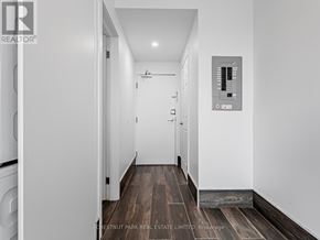 Toronto (Cabbagetown-South St. James Town) condo for rent - A hallway with a washer and dryer on the left and a control panel on the wall.