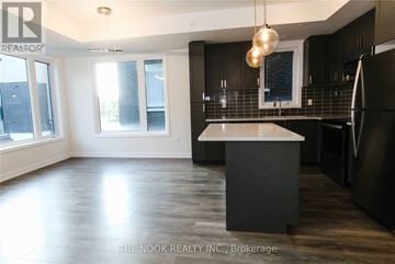 Pickering (Town Centre) townhouse for rent - A modern kitchen with dark wood cabinets and a white island.