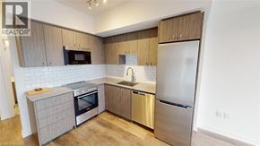 Kitchener condo for rent - A modern kitchen with a stainless steel refrigerator, microwave, and oven.