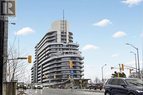 Toronto (Bayview Village) condo for rent - A tall building with a curved top is in the background of a street scene.
