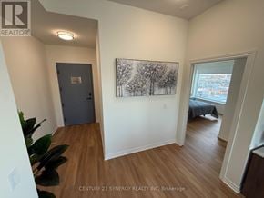 Ottawa apartment for rent - A room with a painting of trees on the wall and a bed in the other room.
