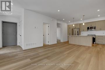 Ottawa multi-family for rent - A spacious room with wooden flooring and a kitchen area with a stove top oven.